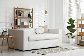 Stylish shelving unit with decor and sofa in room