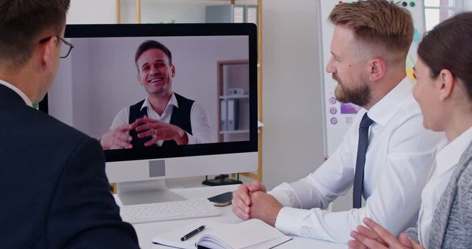 Company employees waving hands having online video call or videoconference with man colleague sitting in meeting room in modern office discussing job project. Business technologies concept. 4k video.