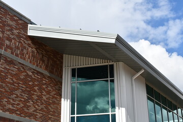 Modern school building, roofline, gutter system, large glass windows.