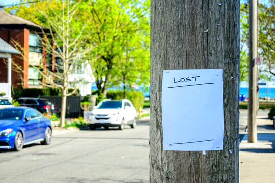 Blank lost handbill stapled to a wooden utility pole right of frame out of focus street scene in background room for text	
 room for text