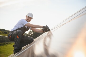Male worker in uniform with a drill screwdriver in his hand near solar panels