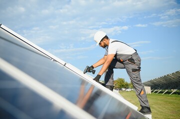 An Indian worker in uniform and with tools works on a solar panel farm