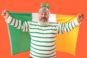 Mature man with Irish flag on orange background. St. Patrick's Day celebration