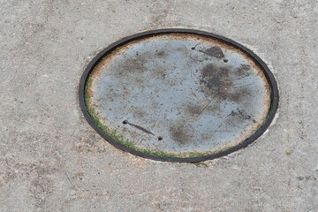 Unmarked manhole in sidewalk.
