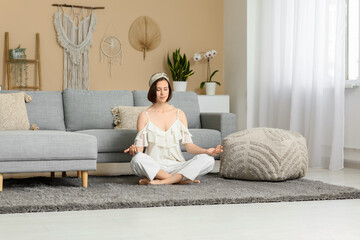 Young woman meditating while sitting on floor at home