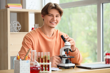 Male student with microscope studying Chemistry at home