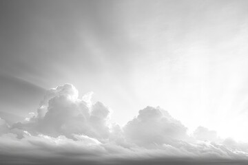 Fototapeta premium Dramatic black and white photograph of large cumulus clouds with sun rays streaming through, creating a serene and majestic sky scene