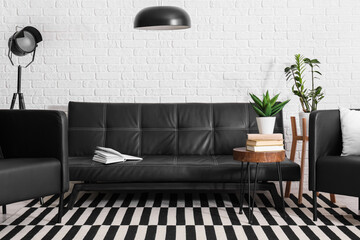 Black leather sofa, coffee table, armchair and lamps in living room