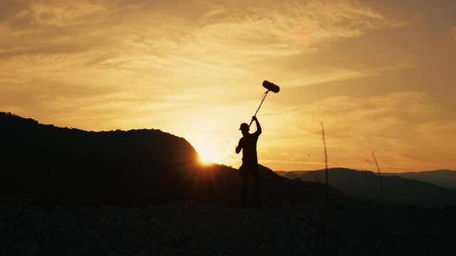 Silhouette Of A Boom Operator Walking On The Mountain Nature At Sunset