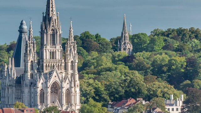 Aerial view of Notre Dame de Laeken church spires under clouds timelapse in Brussels, Belgium. Neo-gothic architecture surrounded by historic facades, green park areas and picturesque urban scenery