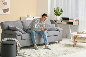 Fototapeta premium Handsome young man in headphones playing video games at home