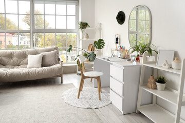 Interior of light dressing room with makeup table, shelf units and sofa