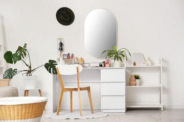 Interior of light dressing room with makeup table, mirror and shelf unit