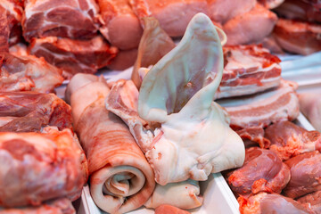 Variety of cuts of raw pork arranged in refrigerated display case of butchery shop. Fresh meat products