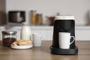 Coffee machine with cup on table in kitchen, closeup