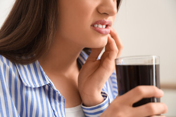 Young woman with soda suffering from toothache in bedroom, closeup