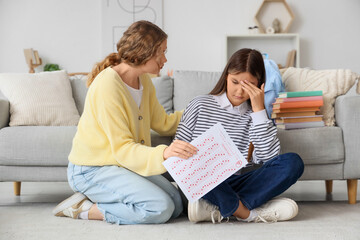 Obraz premium Upset teenage girl and her mother with results of school test at home