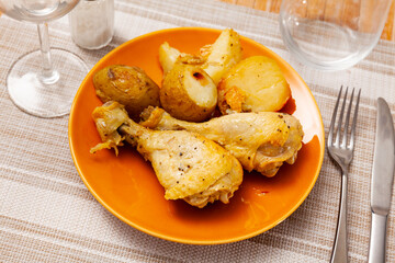 Spicy bbq chicken legs with with boiled potato close-up on a plate