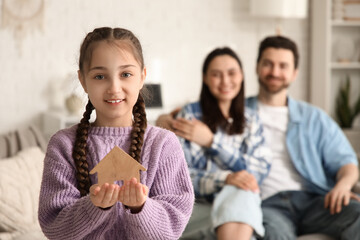 Happy adopted girl with wooden house against parents at home