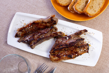 Appetizing roast piece of veal meat dished up in a plate on the laid restaurant table