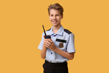 Teenage police officer with radio transmitter on yellow background