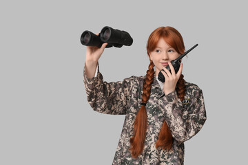 Teenage soldier with radio transmitter and binoculars on grey background
