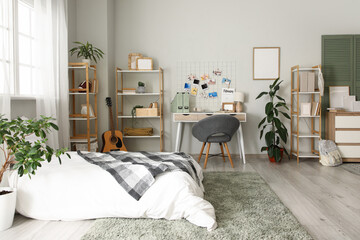 Interior of teenager's room with bed, workplace and shelf units