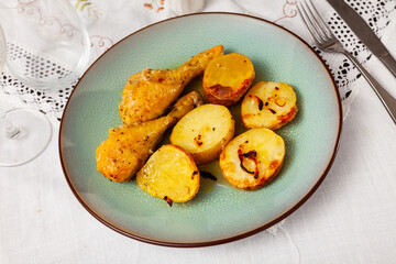 Barbecued chicken leg with boiled potatoes closeup on a plate