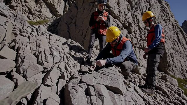 Geologists in helmets analyzing rock layers during outdoor field study