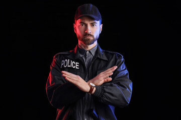 Obraz premium Male police officer showing STOP gesture on black background