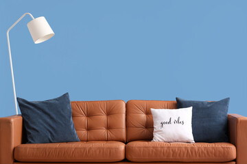 Cozy sofa with cushions and lamp on blue background