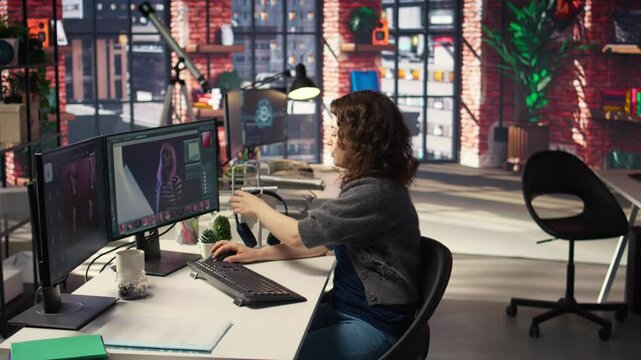 Female editor designer retouches photos on dual monitors desktop, computer setup in a creative office. Ideal workspace for digital media professional focused on photo editing. Camera A.