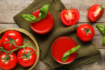 Glasses of fresh tomato juice with basil and vegetables on wooden background
