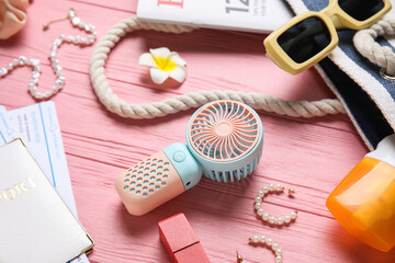 Female summer accessories and mini fan on pink wooden background