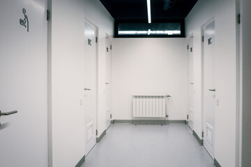 Modern public restroom corridor with white doors labeled 