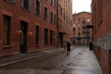 Person walking in the city on wet cobblestone street