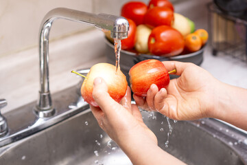 Woman washing organic apple, food disinfection concept