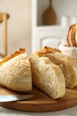 Cut freshly baked bread and knife on table, closeup