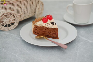 A delicious slice of chocolate cake with cherry topping on a white plate.
