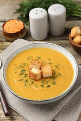 Delicious lentil cream soup served on wooden table, closeup