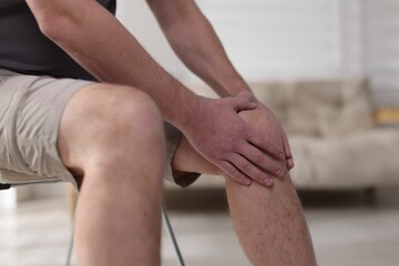 Man suffering from knee pain at home, closeup