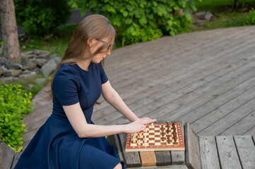 Caucasian woman playing chess outdoors.
