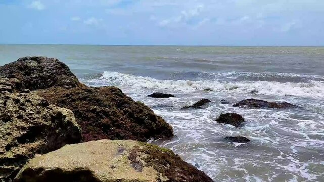 The ocean is calm and the rocks are grey. Puerto Mocho, Bocas de ceniza, Barranquilla, Colombia