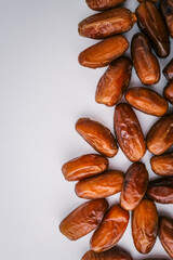 Top view of five dried dates arranged diagonally on a light cream background. Simple organic food layout, perfect for packaging, healthy eating, or clean food concepts