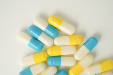 Capsules pill white blue yellow scattered on white surface, health care, medical background