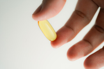 Male hand holding Fish oil capsules with omega 3, omega 9, vitamin D, vitamin E, Cod liver oil