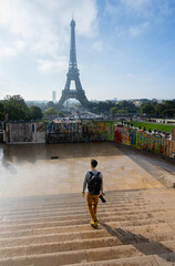 Young Man with Camera and Backpack Walking Toward Eiffel Tower from Trocadero at Sunrise in Paris &ndash; Travel Scene