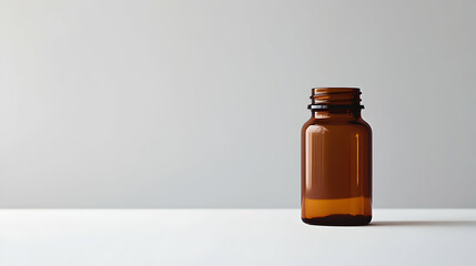 A brown glass bottle stands on a white surface against a neutral background.