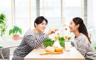 Asian couple  drinking milk and eating vegetable  breakfast  in kitchen at home .