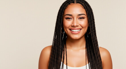 Beautiful woman with black braided hair smiles in front of a neutral backdrop in a studio setting.